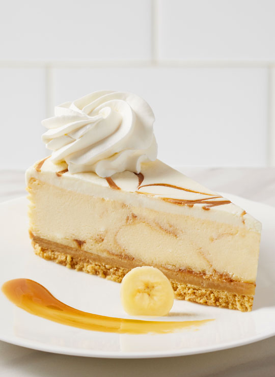A slice of Bananas Foster Cheesecake, garnished with a banana and caramel